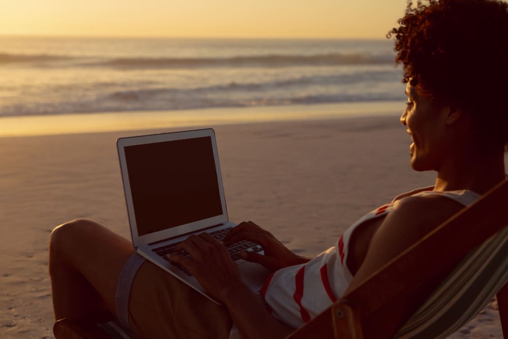 man-using-laptop-while-relaxing-beach-chair-beach (1)